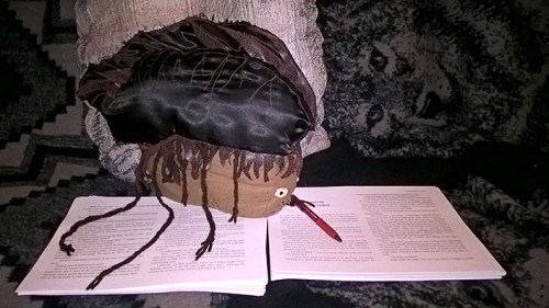 A plushie Legion Spore sits atop a printed manuscript with a red pen