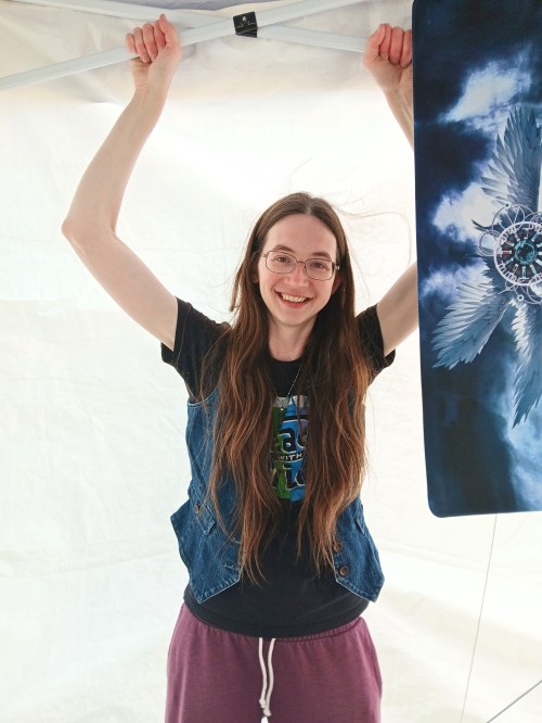 Stephanie smiles while holding the bars on the back of the tent to keep the wind from moving it.