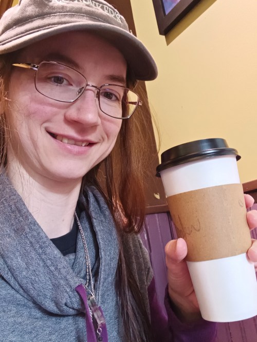 Stephanie holds up a coffee cup from a local coffee shop.